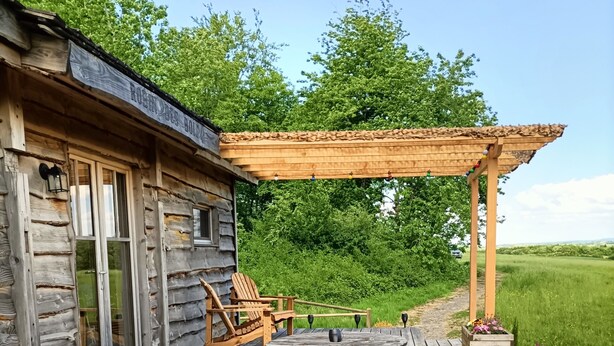 A rustic wooden cabin with a hot tub, wooden deck, outdoor seating, and a pergola. - Cabin “Robin Hood’s Cabin” with Private Terrace and Nordic Bath (Foulcrey)