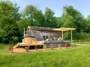Un chalet rustique avec une façade en bois, une véranda dotée de siÚges et un petit jardin.
