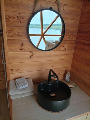 A wooden cabin interior with a round mirror, a sink, and a towel. - A Romantic Getaway: The Dome (Foulcrey)