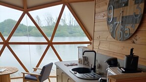 Une cuisine donnant sur un lac, avec des meubles en bois, un évier et une horloge au mur.