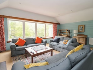 A living room with two grey sofas, a coffee table, and a wooden cabinet. - Culearn Mill (Lochearnhead)