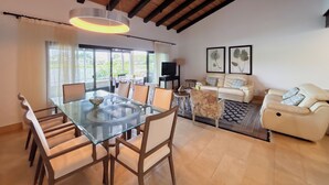 A spacious living area with a glass dining table, a sofa, and a TV. - Splendid 4BR Villa at Buenaventura Resort (Río Hato)