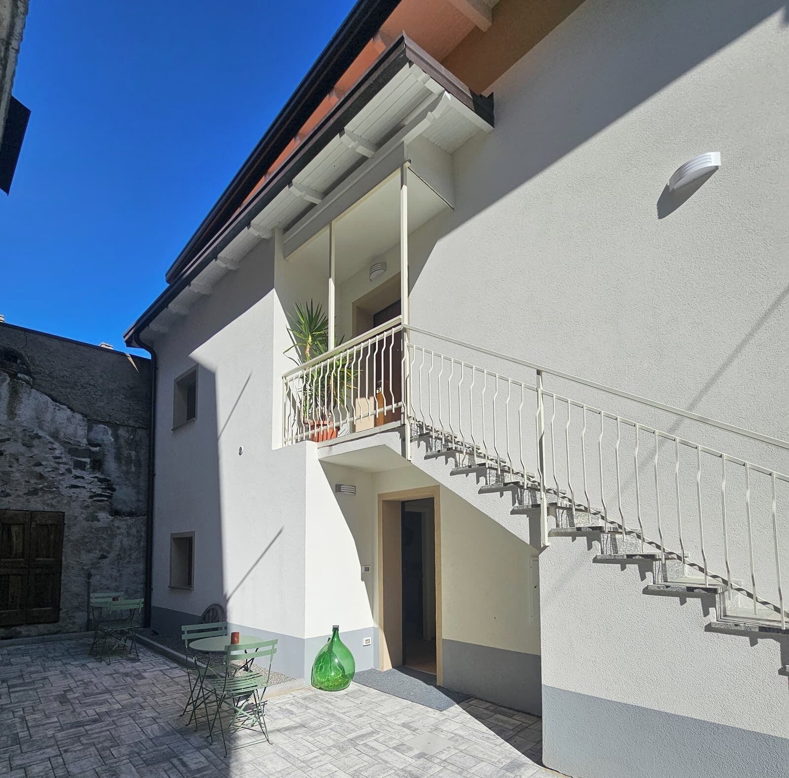 A building with a white exterior, a balcony with metal railings, and a staircase leading to the upper floor.
