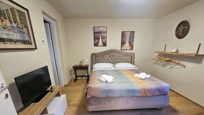 A bedroom with a bed, a television, a small table, and artwork on the walls. - VICOLO STORICO Room - Grandfather Angelo's HOUSE (Capo di Ponte)