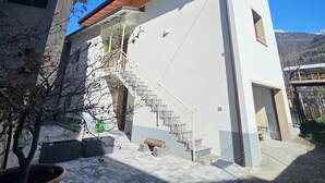 A two-story building with a white exterior, a stone base, and a red roof. - VICOLO STORICO Room - Grandfather Angelo's HOUSE (Capo di Ponte)