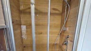 A glass-enclosed shower with a wooden interior, a handheld showerhead, and a door with a metallic handle. - VICOLO STORICO Room - Grandfather Angelo's HOUSE (Capo di Ponte)