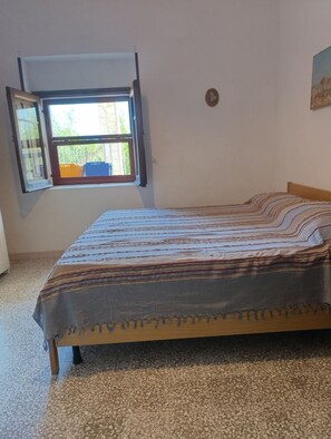 Una habitación con una cama, una ventana y un reloj de pared.