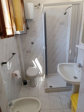 Ein Badezimmer mit Toilette, Bidet, Dusche und Waschbecken.