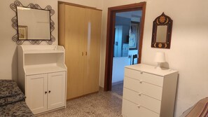Une chambre à coucher avec une armoire, une commode, un miroir et un lit.