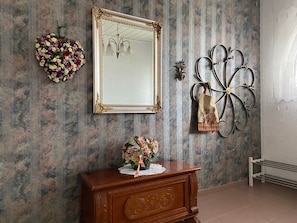 A room with a mirror, a floral arrangement, a decorative metal piece, and a wooden dresser. - 104 m² bright, high-quality apartment with 2 balconies by the forest near Linz (Linz am Rhein)