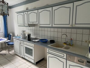 A kitchen with white cabinets, a blue countertop, a sink, and a stove.