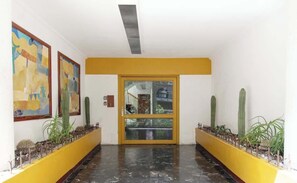 A hallway with yellow walls, a marble floor, and two large paintings on the left. - Location- Design and Comfort Fully Equipped (Mexico City)