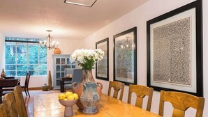 Ein Esszimmer mit einem Holztisch, Stühlen, einer Vase mit Blumen und gerahmten Bildern an der Wand.