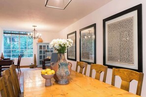 A dining room with a wooden table, chairs, a vase with flowers, and framed artwork on the wall. - Location- Design and Comfort Fully Equipped (Mexico City)