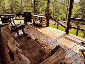 A wooden deck with a bench and a table, surrounded by a railing.