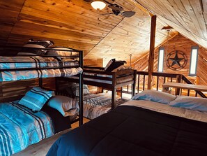 A cozy attic bedroom with bunk beds, a wooden ceiling, and a star decoration.
