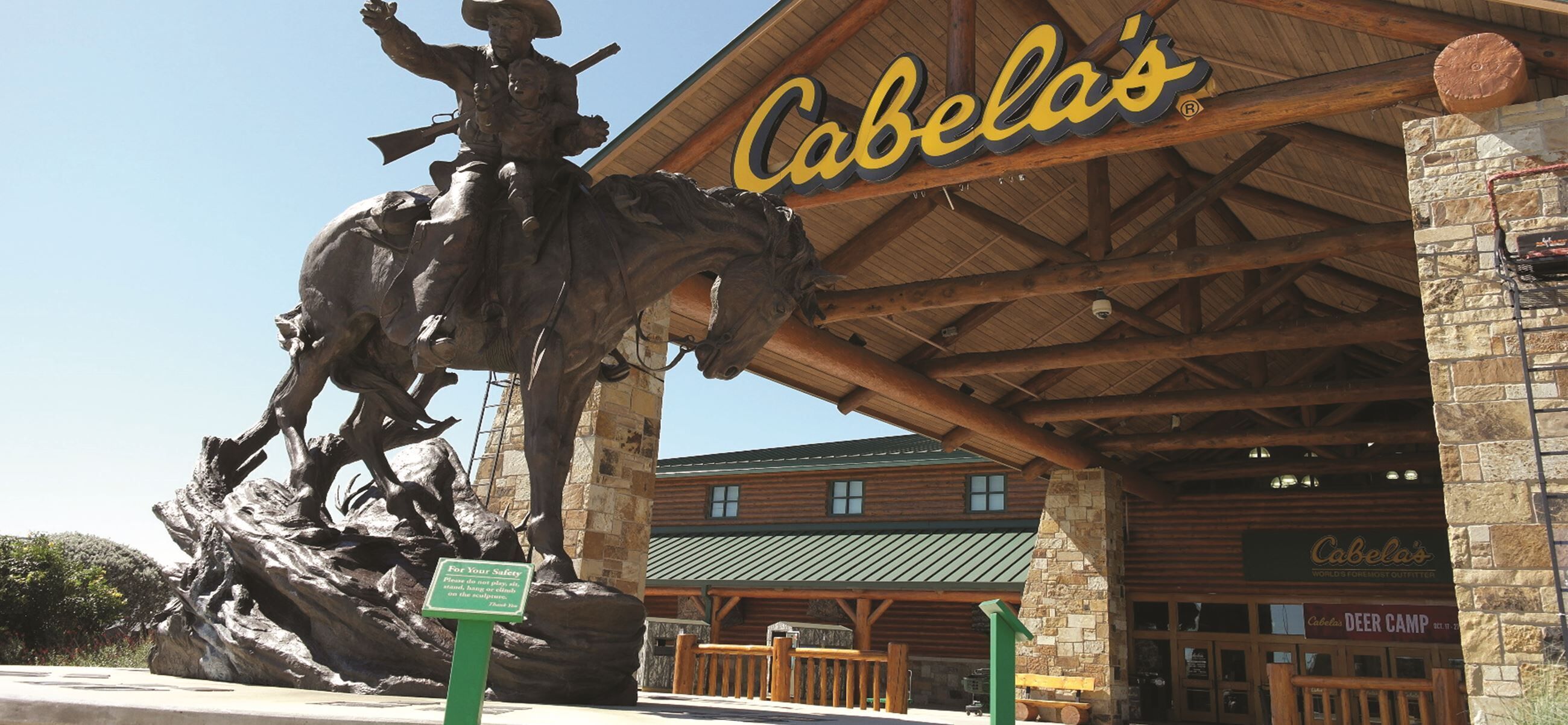 Un bâtiment rustique en bois, sur lequel on peut lire en grandes lettres l’inscription « Cabela’s », et qui est agrémenté d’une sculpture imposante placée à l’extérieur.