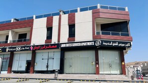 A multi-story building with a sign for 'LAVIN SUITES SERVICED APARTMENTS' and another sign in a different language. - LAVIN SUITES SERVICED APARTMENTS  (At Taif)