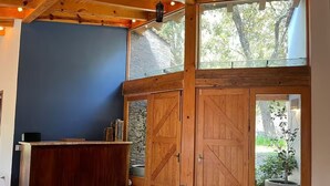 A room with a wooden reception desk, large wooden doors, a stone wall, and a view of greenery outside. - CABAÑA RANCHO SAN FRANCISCO TAPALPA (Tapalpa)