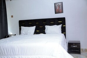 Ein Hotelzimmer mit einem großen Bett, einem Nachttisch, einem gerahmten Bild an der Wand und einem Marmorboden.
