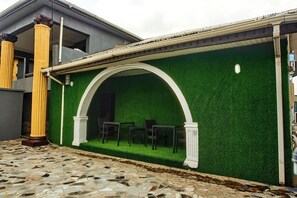 Ein Gebäude mit einer grünen Wand aus Kunstgrün, einer weißen Bogenkonstruktion und einer gefliesten Terrasse.