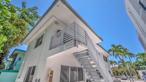 Ein zweigeschossiges Gebäude mit weißer Fassade, einem sichtbaren Feuerlöscher und einer Treppe, die zum oberen Stock führt.