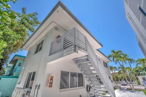 A two-story building with a white exterior, a visible fire extinguisher, and a staircase leading to the upper floor. - #2 - Beachside Studio  Steps to Hollywood Beach (Hollywood)