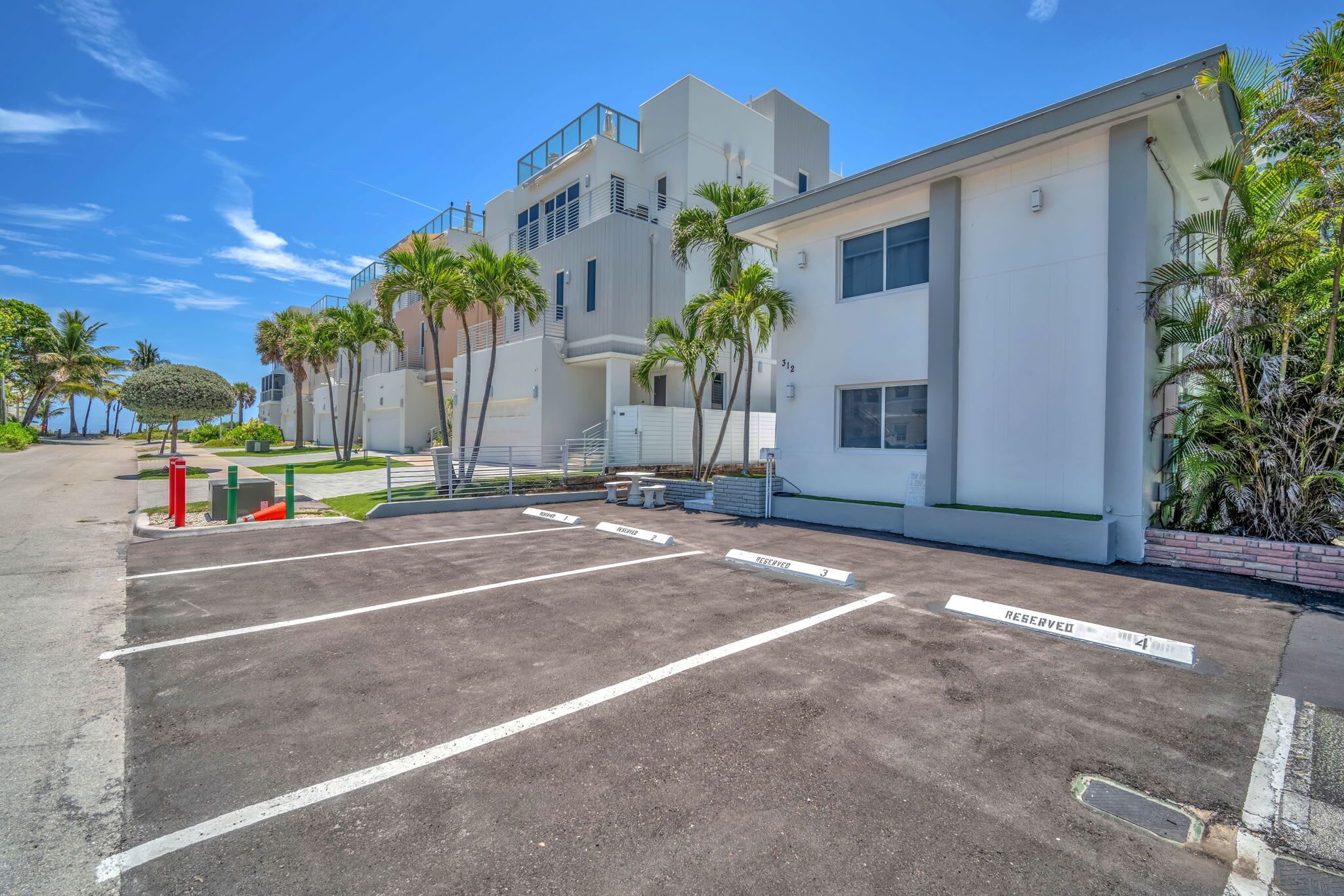 A parking lot with marked spaces, a fire hydrant, and a building with modern architecture.