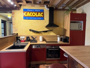Eine Küche mit Holzarbeitsplatte, einem Bosch-Backofen, einem Spülbecken und einem Schild mit der Aufschrift 'Chaud ou Glace CACOLAC'.