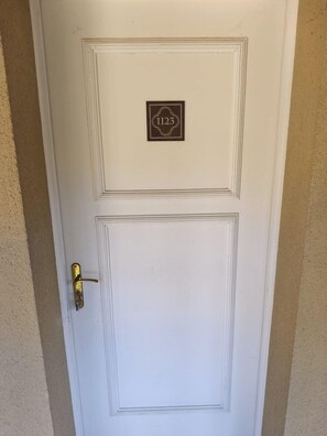 A white door with a brass doorknob and a plaque with the number '1123'.