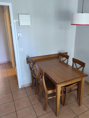 Un comedor con una mesa y sillas de madera, una pared blanca y una lámpara.