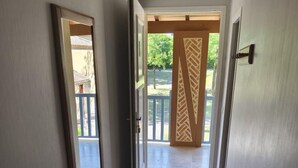 Un pasillo con suelo de baldosas que conduce a una puerta abierta con un panel decorativo.