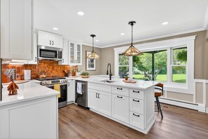 A modern kitchen with white cabinets, a stainless steel stove, and pendant lighting.