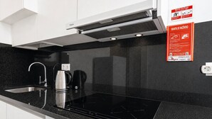A modern kitchen with a black countertop, stainless steel sink, and a built-in induction cooktop. - Cedofeita Cozy by Hosty (Porto)