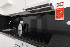 Eine moderne Küche mit schwarzem Arbeitsplatz, Spüle aus Edelstahl und integriertem Induktionskochfeld.