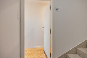 Ein Flur mit Holzboden, einer weißen Tür mit einem Schild und einer Treppe.