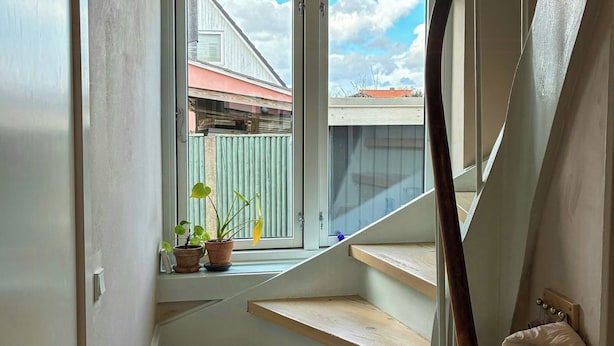 A staircase with wooden steps leading to a window overlooking a residential area. - Townhouse with art and terrace (København)
