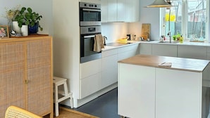 A modern kitchen with white cabinetry, a built-in oven, and a large window. - Townhouse with art and terrace (København)