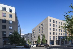 Ein mehrgeschossiges Gebäude mit Parkplatz davor.