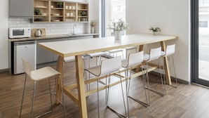 Eine moderne Küche mit einem Holztisch, Barhocker, einer eingebauten Mikrowelle und Blick auf die Straße.