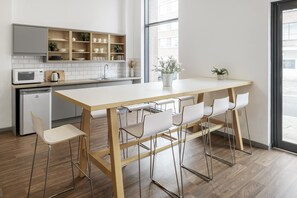 Eine moderne Küche mit einem Holztisch, Barhocker, einer eingebauten Mikrowelle und Blick auf die Straße.