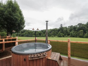 A hot tub on a wooden deck with a view of a grassy field and trees. - Copper Suite (Chulmleigh)