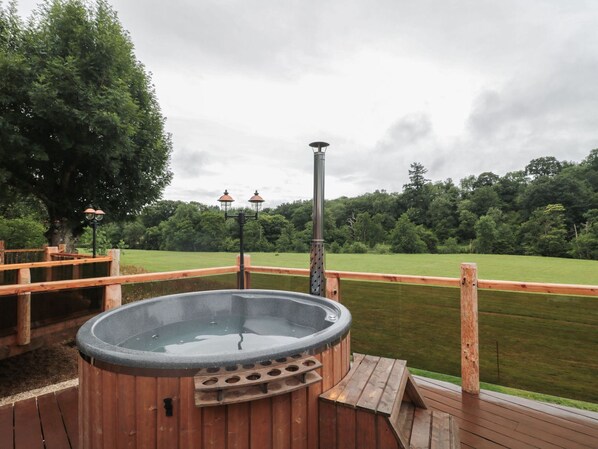 A hot tub on a wooden deck with a view of a grassy field and trees. - Copper Suite (Chulmleigh)