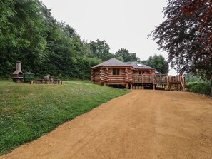 A rustic log cabin with a dirt driveway leading to a wooden deck. - Copper Suite (Chulmleigh)