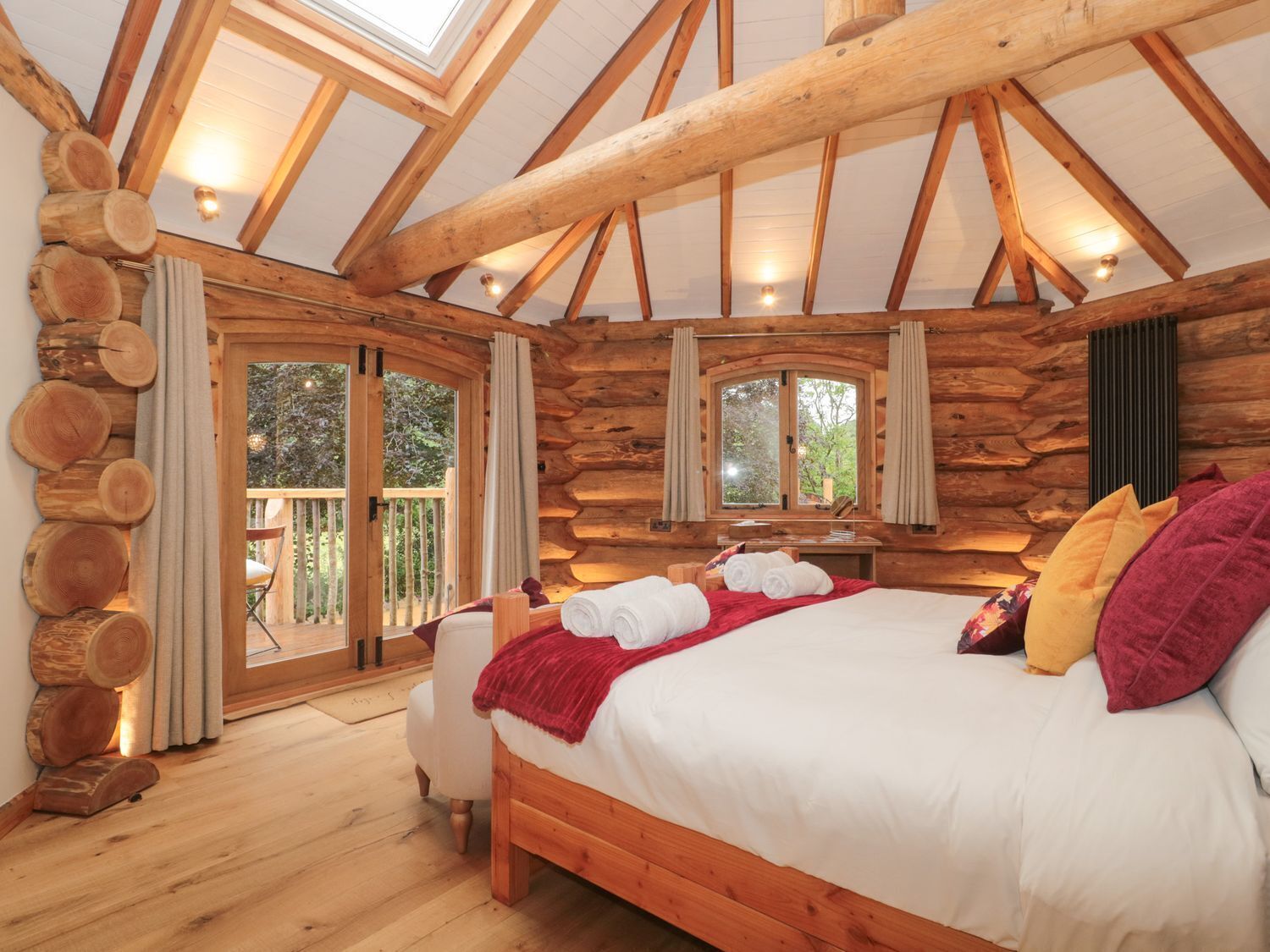 A log cabin bedroom with a bed, curtains, and a window.
