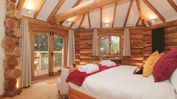 A log cabin bedroom with a bed, curtains, and a window.