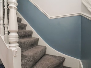 Escada com corrimão branco e parede azul.