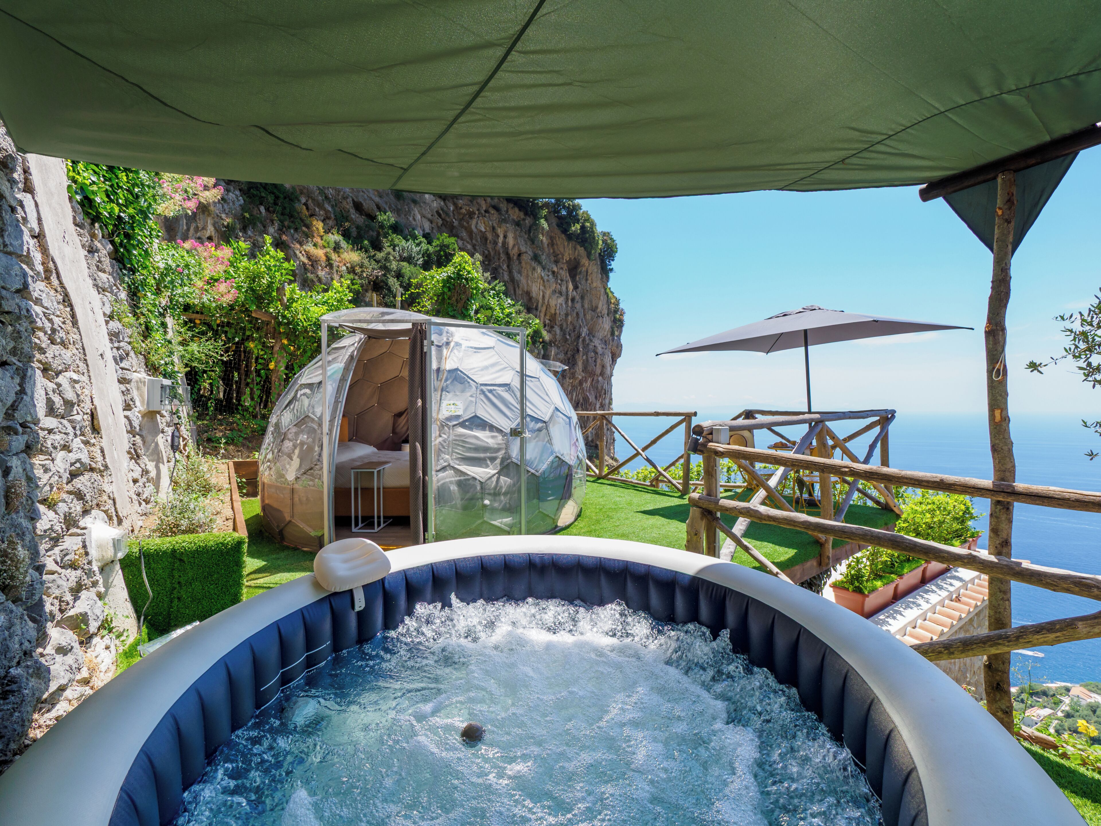 Un bain à remous avec une vue dégagée sur la mer, une tente en forme de dôme et une terrasse en bois.