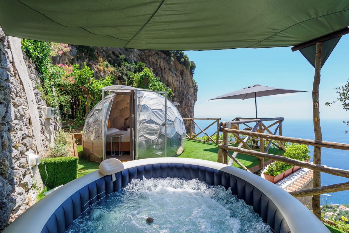 Ein Whirlpool mit freiem Blick auf das Meer, ein kuppelförmiges Zelt und eine Holzterrasse.