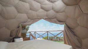 A tent-like structure with a bed inside, a view of the outdoors, and a wooden table. - De Vivo Realty - Boscosfera Amalfi (Amalfi)